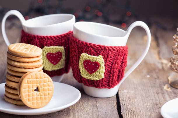 Two cute cups of coffee with hearts in red fabric on them.