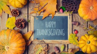 Pumpkins and leafs around a blackboard that says Happy Thanksgiving