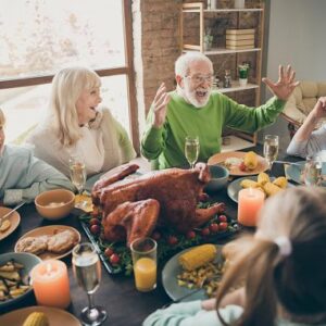 A family laughing together at their Thanksgiving dinner.