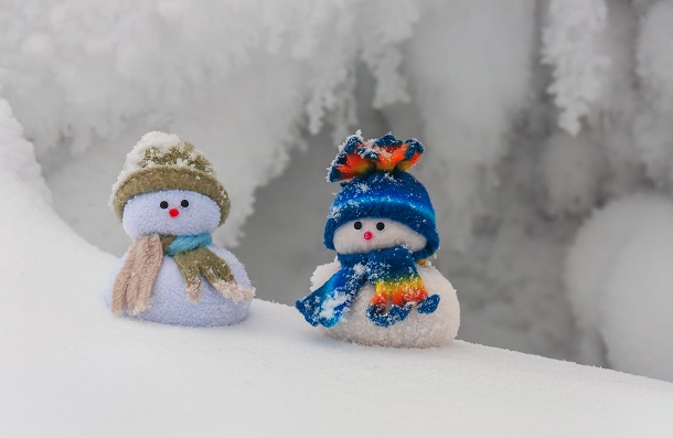 Two tiny snowmen standing in the snow of winter.