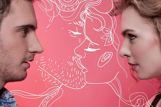 An image of a man and a woman looking into each other's eyes with a drawing behind them on the wall of them kissing.