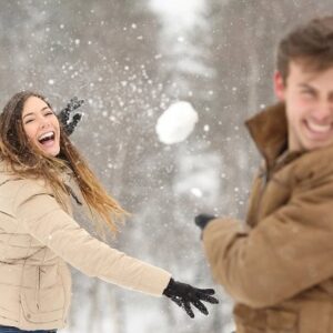 A couple having fun with a snowball fight.