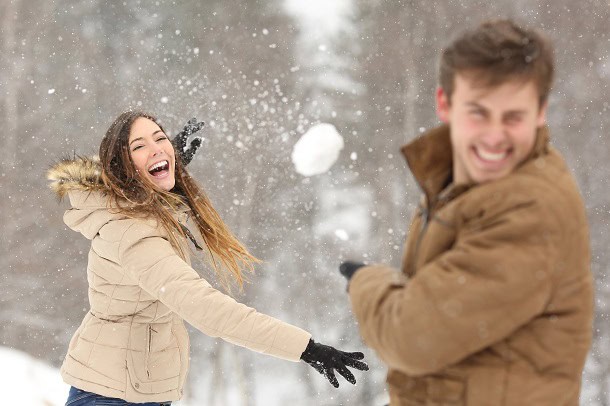 A couple having fun with a snowball fight.