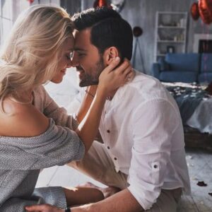 A couple sitting and hugging with their foreheads lovingly against each other.