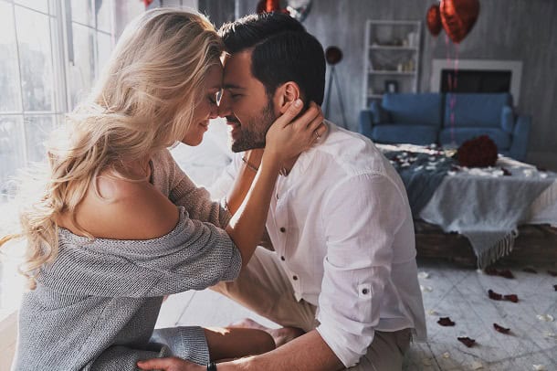 A couple sitting and hugging with their foreheads lovingly against each other.