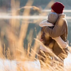 A couple embracing by a lake in the fall.