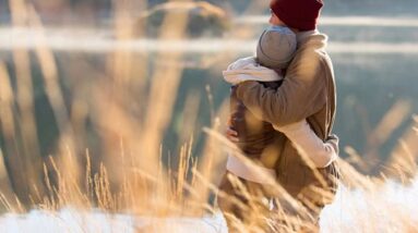 A couple embracing by a lake in the fall.