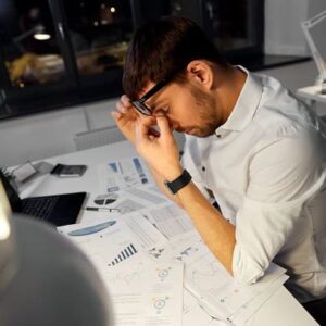 A tired looking man working late at night in an office.