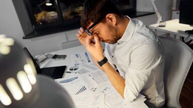 A tired looking man working late at night in an office.