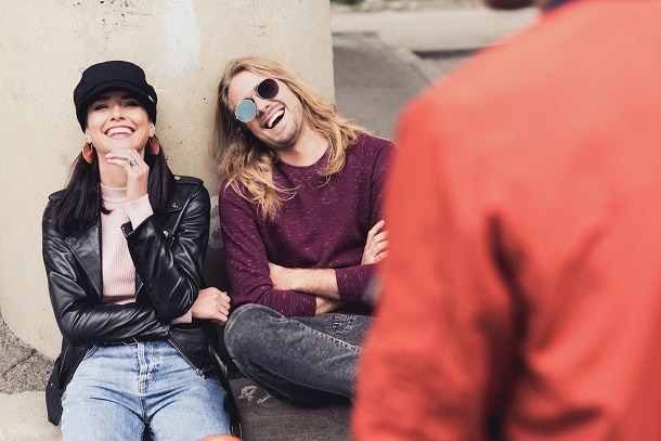 Friends laughing together while sitting outside.