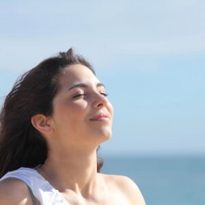 A woman breathing and finding inner peace by the ocean.