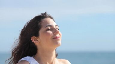 A woman breathing and finding inner peace by the ocean.