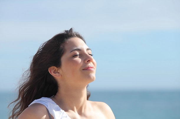 A woman breathing and finding inner peace by the ocean.