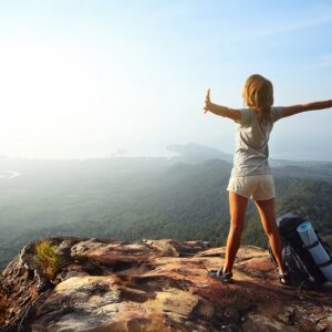 A happy woman with her arms stretched out at the top of a mountain.