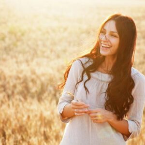 A happy woman smiling while standing in a field.