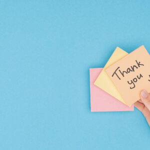 A hand holding a post-it that says: Thank you