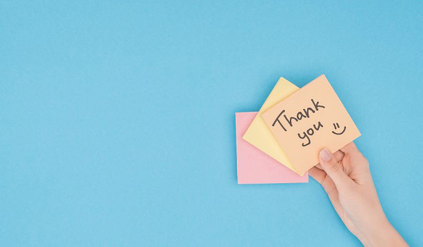 A hand holding a post-it that says: Thank you