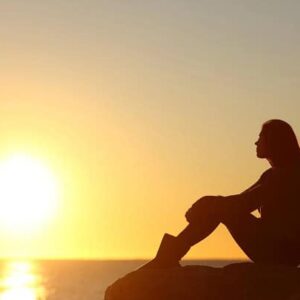 A woman looking at a sunset over the ocean.