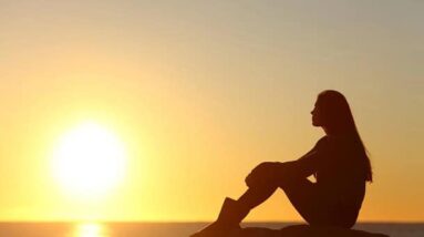 A woman looking at a sunset over the ocean.