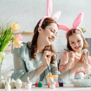 Mother and daughter having fun while painting Easter eggs.