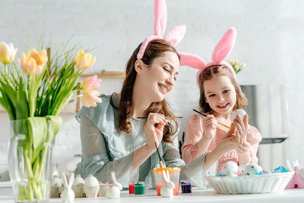 Mother and daughter having fun while painting Easter eggs.