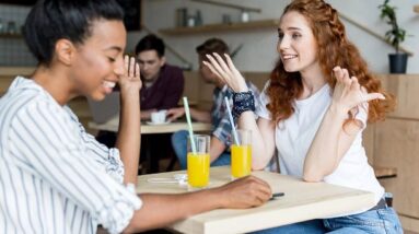 Two girls having a good time in a cafe with juice glasses.