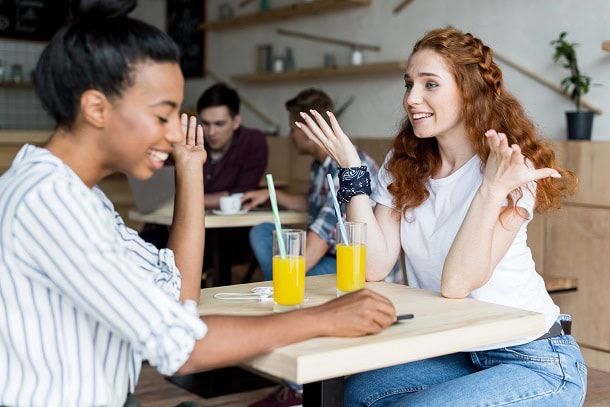 Two girls having a good time in a cafe with juice glasses.