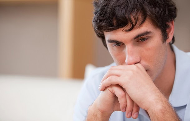 A man sitting down and looking thoughtful.