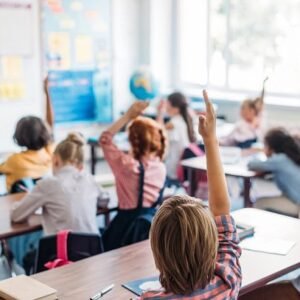 Kids sitting in class with their hand up.