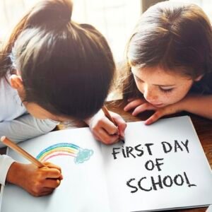 Two girls in school coloring a rainbow and writing: First Day of School.