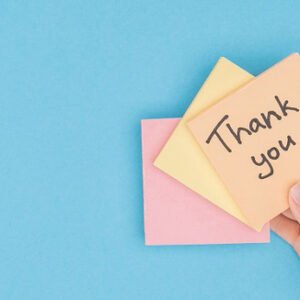 A hand holding up a note saying: Thank you :)