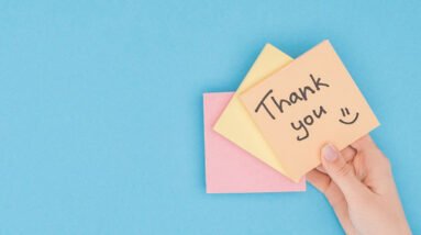 A hand holding up a note saying: Thank you :)