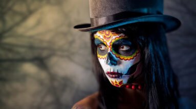 A young woman with a high hat and a her face painted for Halloween.