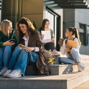 Girls having fun while sitting on the stairs leading to the school.