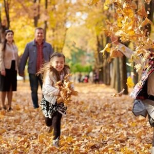 Children running and throwing autumn leaves while their parents watch them smiling.