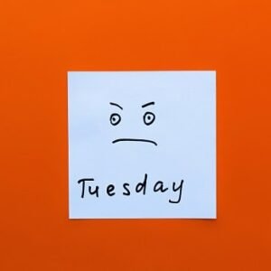 A somewhat irritated or angry smiley on a post-it note with the word Tuesday written below it.
