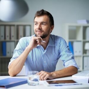 A man looking optimistic while sitting at his desk at work.