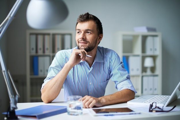 A man looking optimistic while sitting at his desk at work.