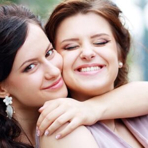 A woman hugging another woman while both are smiling.