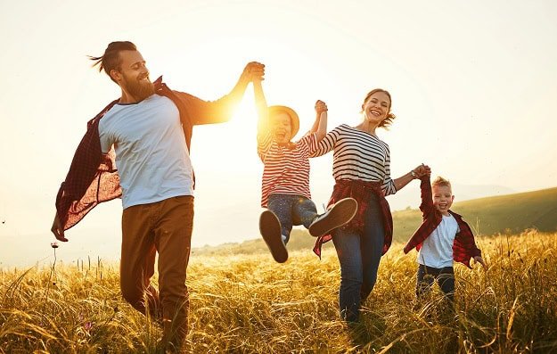 A happy family running in a summer field.