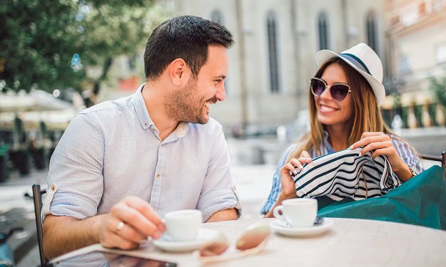 A happy couple sitting outside and having coffee.