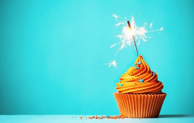A sparkler sparkling in a decorated birthday cupcake.