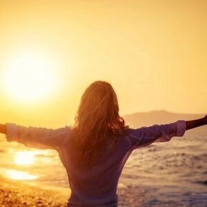 A woman on the beach at sunrise.