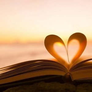 A heart made of two pages in an open book with a sunrise on the horizon.