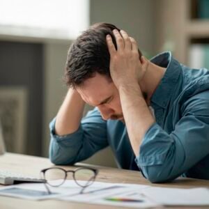 Man looking stressed and upset while sitting at his work desk.