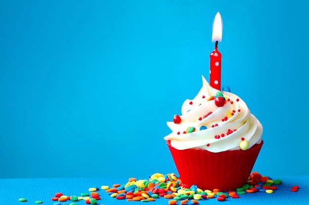 A cupcake with a single lit candle in the middle of it.