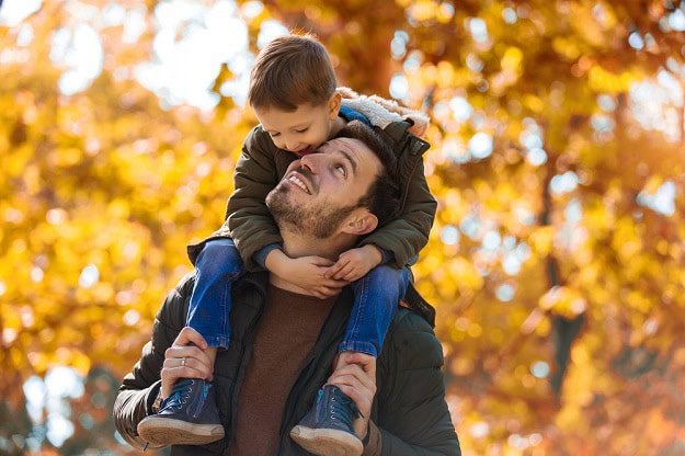 A smiling son riding on his father